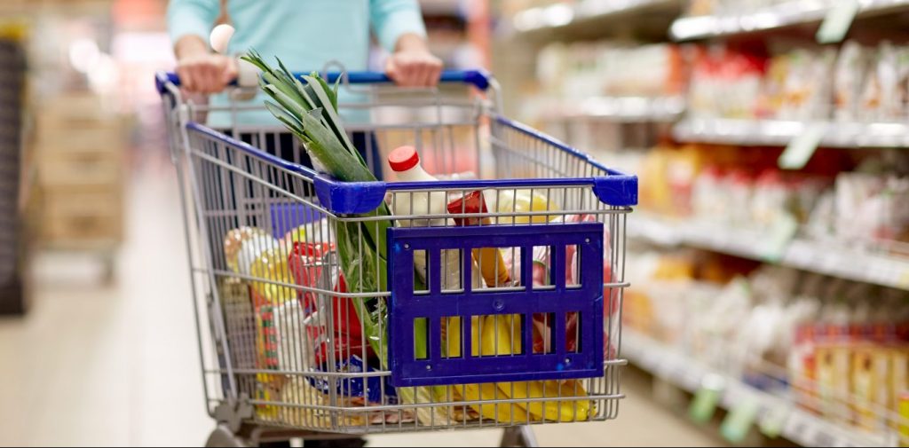 woman with food in shopping cart at supermarket